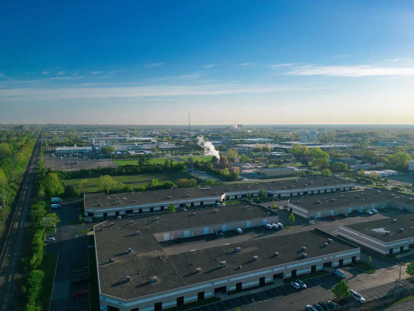 Aerial view of a sprawling industrial park with warehouse buildings, parking lots, and access roads.